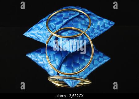 Gold mirror-effect earrings on a black background Stock Photo