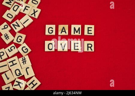 "Game over" phrase on a red felt background surrounded by wooden letter tiles Stock Photo