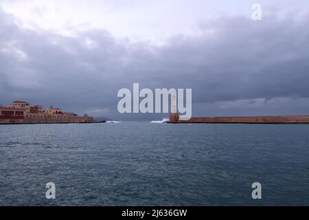 Chania's seafront onto the water and it's lighthouse at a cloudy day in fall, Crete, Greece 2021 Stock Photo