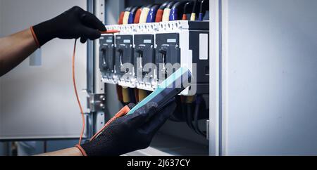 Electrical engineers check electrical control devices with a multimeter. Stock Photo