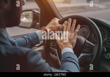 Unrecognized male pushing on the wheel of the automobile Stock Photo