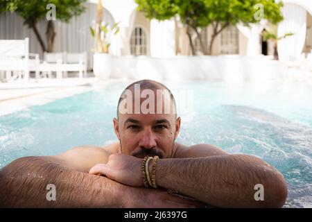 Man relaxing in pool on vacation in Riyadh, Morocco Stock Photo