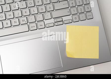 directly above view of blank yellow sticky note on laptop computer Stock Photo