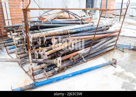 a bunch of telescopic jack stands for mounting the formwork of a monolithic ceiling lie in a cradle made of reinforcement prepared for lowering from t Stock Photo