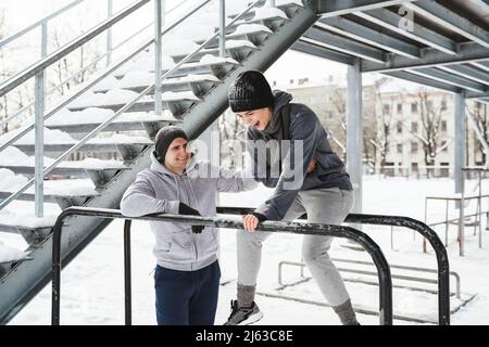 Young sportive couple during calisthenics workout during winter and snowy day Stock Photo
