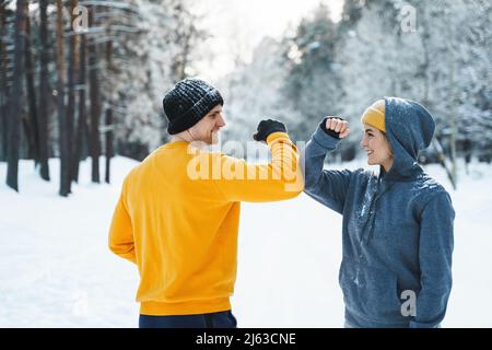 Two joggers greeting each other with a elbow bump gesture during winter workout Stock Photo