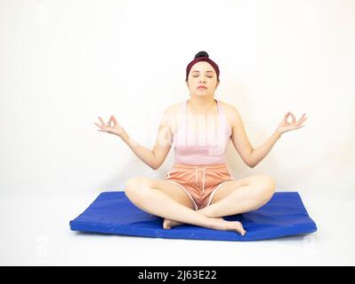beautiful woman in loto yoga pose with raised head and closed eyes on blue mat Stock Photo