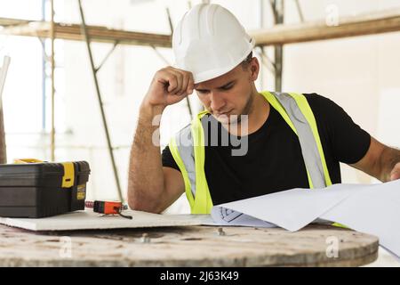 Worker is checking blueprints during his work on a construction site Stock Photo