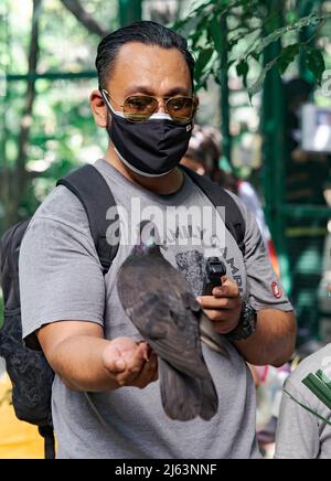 Kuala Lumpur, Malaysia - Oct 14, 2021 : A man wearing sunglasses holding a pigeon on his hand. Stock Photo