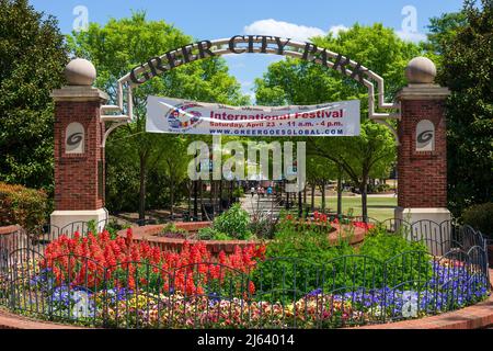GREER, SC, USA 24 APRIL 2022: View of entrance to Greer City Park, with flower beds in front and people in distance on sidewalk.  Banner sign for Inte Stock Photo
