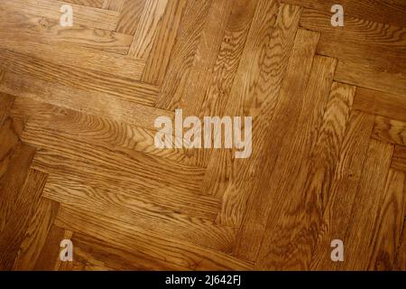 Classic wooden oak parquet in the form of a dark brown Christmas tree. Brown seamless parquet floor with a pattern of spruce from narrow boards. Stock Photo