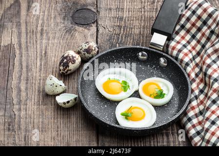 Fried  quail eggs in onion ring in frying pan on wooden table Stock Photo
