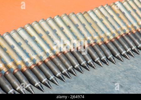 Number of cartridges from machine gun folded in a row on a orange background Stock Photo