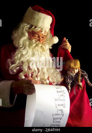 Santa Claus holding his bag of toys while checking his list of good children. Stock Photo
