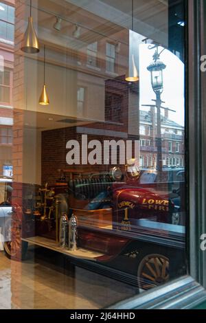 A view through a glass window of a vintage red fire engine (Chemical Hose 1) parked inside a building. The building is located in the historic district Stock Photo