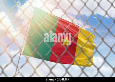 A steel mesh against the background of a blue sky and a flagpole with the flag of cameroon Stock Photo