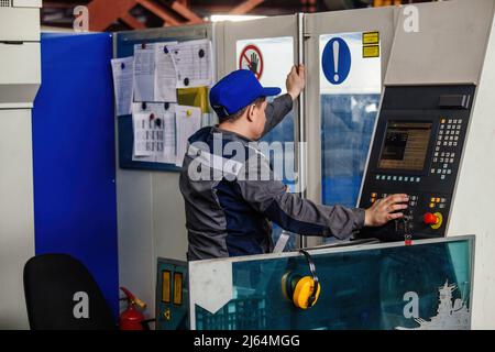 Factory worker operating CNC machine in metalworking workshop. Stock Photo