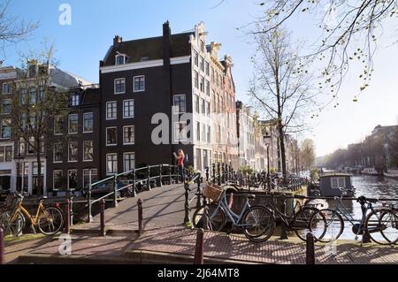 Young woman taking a photo on a bridge at corner of Brouwersgracht and Herengracht canal, Jordaan, Amsterdam, North Holland, Netherlands, Europe Stock Photo