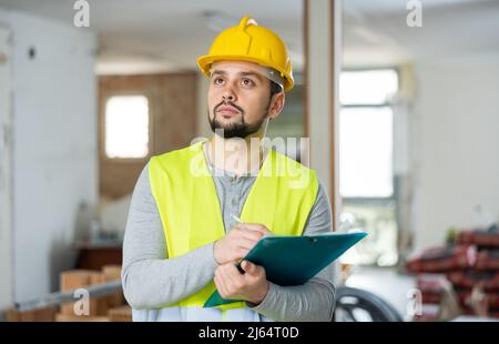 Focused supervisor taking notes while inspecting construction site Stock Photo