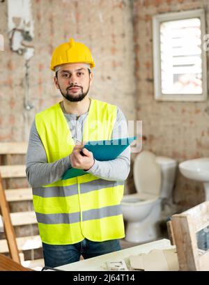 Builder making notes on indoor construction site Stock Photo