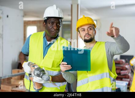 Two builders talking on indoor construction site Stock Photo