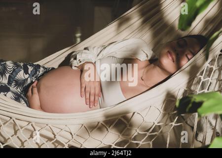 Pregnant woman happy seeing sunset relax lying in a hammock Stock Photo