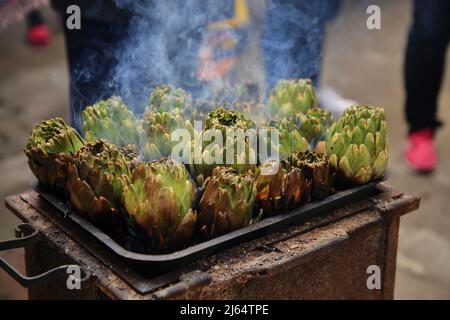 April 24, 2022, Pagani, Campania/Salerno, Italy: During the days of the Feast of Our Lady of Mount Carmel, called ''of the hens'', the traditional food of this religious festival is prepared for the historic center. Women cook artichokes on small kilns, while men prepare in large pots the sauce to be used for the traditional homemade pasta called ''tagliolini' (Credit Image: © Pasquale Gargano/Pacific Press via ZUMA Press Wire) Stock Photo
