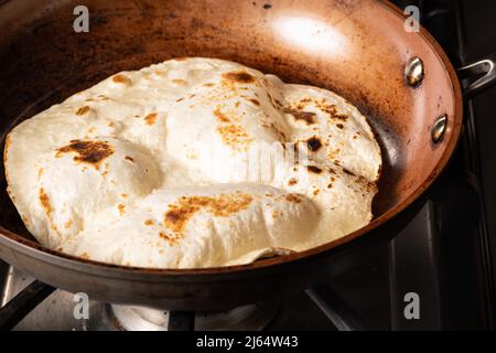 Cooking Tandoori Roti in frying pan, a typical flatbread and popular in West, Central and South Asia. Stock Photo