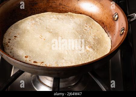 Cooking Tandoori Roti in frying pan, a typical flatbread and popular in West, Central and South Asia. Stock Photo