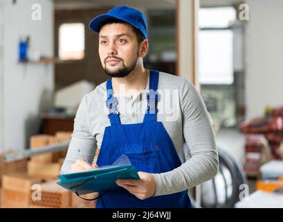 Focused contractor inspecting rooms and taking notes during renovation Stock Photo
