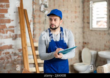 Focused contractor inspecting rooms and taking notes during renovation Stock Photo