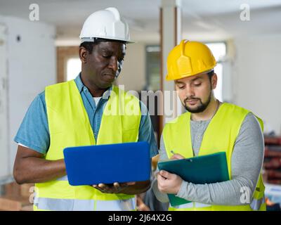 Two builders talking on indoor construction site Stock Photo