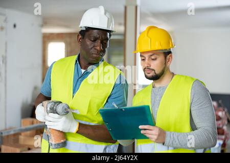 Two builders talking on indoor construction site Stock Photo