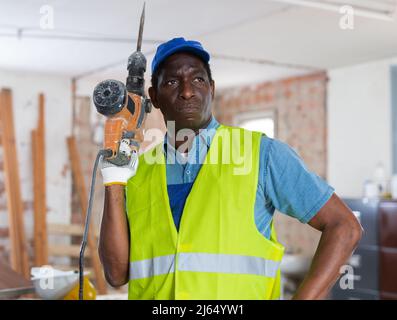 Professional builder holding pneumatic chipping hammer in building under construction Stock Photo