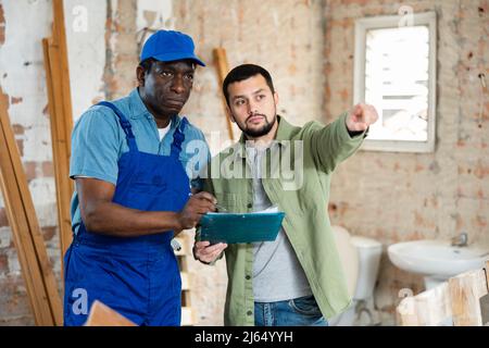 Builder having conversation with designer about working plan Stock Photo