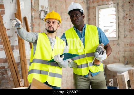 Two builders talking on indoor construction site Stock Photo