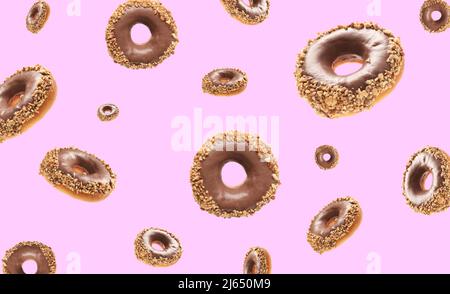 Many flying chocolate donuts on pink background Stock Photo