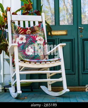 White rocking chair with colorful cushion on front porch of historic home in New Orleans, LA, USA on April 9, 2022 Stock Photo
