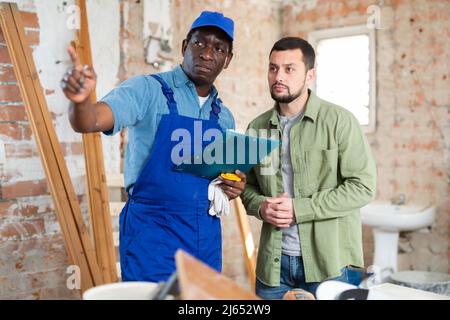 Builder having conversation with designer about working plan Stock Photo