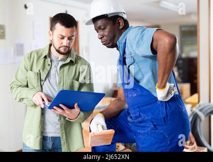 Two men talking on indoor construction site Stock Photo
