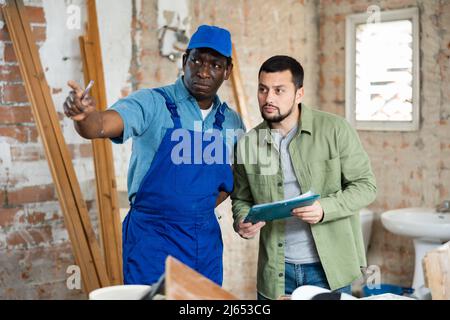 Builder having conversation with designer about working plan Stock Photo