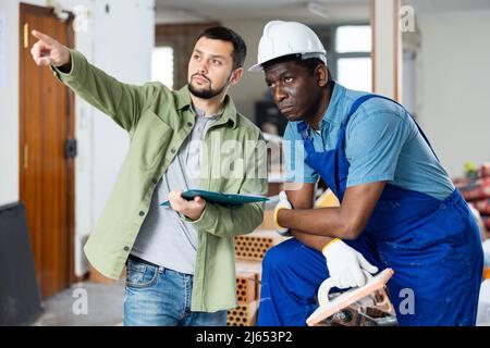Builder having conversation with designer about working plan Stock Photo