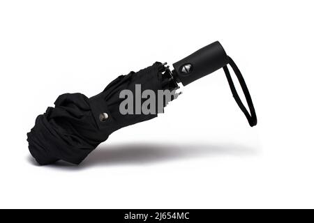 Close up of black folded closed small umbrella peck with automatic opening and black hand flap on white background Stock Photo