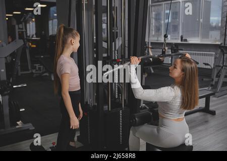 back view of sportswoman doing arms and back extension exercise on lat  machine Stock Photo - Alamy