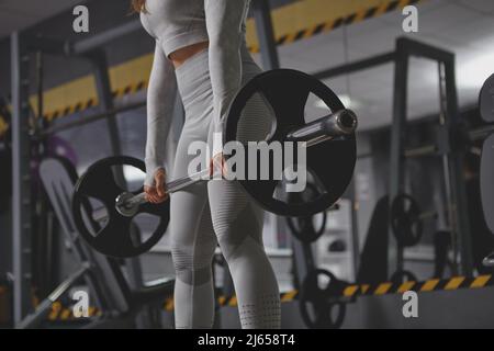 Low angle cropped shot of unrecognizable sportswoman lifting heavy barbell at the gym Stock Photo