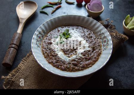 Dal makhni or dal makhani is a north Indian recipe using black lentils and red kidney beans served in a bowl on a dark background. Top view. Stock Photo