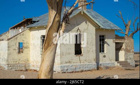 Former crumbled train station in a lonely area in Garub the south of Namibia, Africa. It is an empty and dilapidated white building, with desert sand Stock Photo