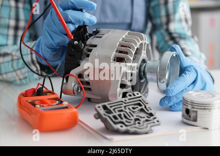 Handyman in gloves repairing automobile part and measuring voltage Stock Photo