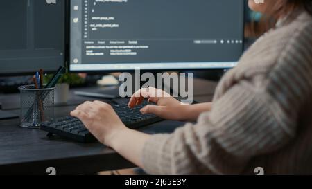 Closeup of caucasian software coder hands typing on keyboard in front of computer screens with programming interface. Database developer sitting at desk writing algorithm for it agency. Stock Photo