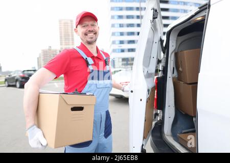 Smiling courier with parcels near delivery van Stock Photo